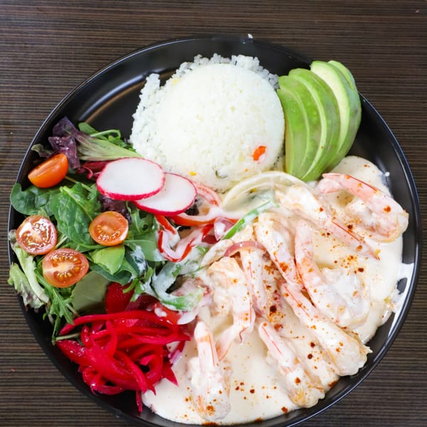 Lempira Restaurant's creamy shrimp dish with rice, avocado, salad, radishes, and pickled onions.